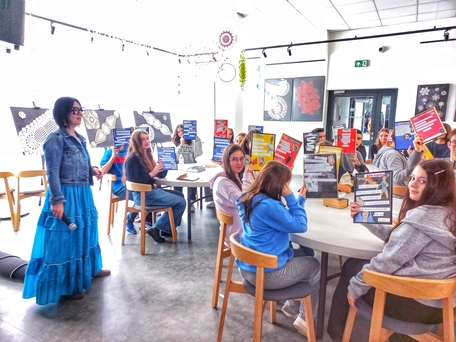 Pani prowadząca zajęcia i młodzież trzymająca swoje prace